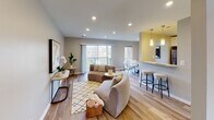 Located at 3130 Normandy Woods Dr in Ellicott City, Maryland, this well-appointed single-floor residence offers a thoughtfully designed layout that balances comfort and modern style. The open-concept living and dining area is anchored by warm hardwood-style flooring, recessed lighting, and large sliding glass doors that flood the space with natural light and provide direct access to a private balcony overlooking a lush green landscape. The living area flows naturally into a dining space featuring a striking oval marble-top table, framed by windows with scenic outdoor views. The kitchen is equipped with stainless steel appliances including a gas range and dishwasher, complemented by rich stone countertops with dramatic veining, a built-in sink, and crisp white cabinetry offering ample storage. A breakfast bar with pendant lighting connects the kitchen to the main living space. The bedroom features plush carpeting, a ceiling fan, and a generously sized window that brings in plenty of natural light while offering pleasant outdoor views. An additional bedroom provides a quiet, carpeted retreat with neutral tones. The bathroom is finished with large-format neutral tiles surrounding a soaking tub and shower combination, chrome fixtures, and clean, contemporary detailing throughout.