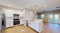 Located at 101 Haven Blvd in Palm Coast, Florida, this well-appointed single-story home offers three bedrooms, three bathrooms, and a thoughtfully designed floor plan. The open-concept kitchen and living area serves as the heart of the home, showcasing white shaker cabinetry, quartz countertops, a central island with a double sink, stainless steel appliances including a refrigerator, range, microwave, and dishwasher, and elegant pendant lighting overhead. Light-toned wood flooring flows throughout the entire home, lending warmth and continuity to every room. The primary bedroom is generously sized, featuring a ceiling fan, sliding glass doors that open to an outdoor patio with green views, and an en suite bathroom complete with a double vanity, a frameless glass walk-in shower, and a private water closet. The additional bedrooms each include ceiling fans, natural light from windows with blinds, and built-in closets. Bathrooms throughout maintain a clean, modern aesthetic with white cabinetry and bright finishes. The home also includes a dedicated laundry area, a pantry, and four closets for ample storage. Detached garage units are available on the property, complemented by well-maintained landscaping with palm trees and manicured greenery.
