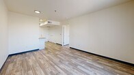 Located at 200 Valencia Dr SE in Albuquerque, New Mexico, this single-floor, one-bedroom, one-bathroom unit offers a functional and efficiently designed layout. Wood-look flooring runs throughout the space, complemented by crisp white walls and dark baseboards that provide a clean, modern contrast.

The kitchen is well-appointed with white cabinetry, granite-style countertops, black appliances including a range and full-size refrigerator, a range hood, and a sink with ample counter space on both sides. A skylight above the kitchen fills the area with natural light. The kitchen opens directly to the combined dining and living area, which benefits from a large window offering outdoor views of the surrounding landscape.

The primary bedroom is a comfortable, dedicated room with its own large window that brings in natural light and overlooks a natural outdoor setting. Two closets provide generous storage options within the unit.

The bathroom is equipped with a full tub-shower combination, a white vanity with granite-style countertop, and wood-look flooring that ties the space together cohesively. A dedicated laundry room with hookups adds everyday convenience. The overall layout is straightforward and practical, designed to maximize usability within a compact, single-story footprint.