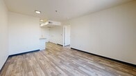 Located at 200 Valencia Dr SE in Albuquerque, New Mexico, this single-floor, one-bedroom, one-bathroom unit offers a functional and efficiently designed layout. Wood-look flooring runs throughout the space, complemented by crisp white walls and dark baseboards that provide a clean, modern contrast.

The kitchen is well-appointed with white cabinetry, granite-style countertops, black appliances including a range and full-size refrigerator, a range hood, and a sink with ample counter space on both sides. A skylight above the kitchen fills the area with natural light. The kitchen opens directly to the combined dining and living area, which benefits from a large window offering outdoor views of the surrounding landscape.

The primary bedroom is a comfortable, dedicated room with its own large window that brings in natural light and overlooks a natural outdoor setting. Two closets provide generous storage options within the unit.

The bathroom is equipped with a full tub-shower combination, a white vanity with granite-style countertop, and wood-look flooring that ties the space together cohesively. A dedicated laundry room with hookups adds everyday convenience. The overall layout is straightforward and practical, designed to maximize usability within a compact, single-story footprint.