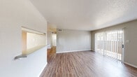 Located at 2201 Rocky Lane in Odessa, Texas, this single-floor residence offers a practical and functional layout with a clean, neutral aesthetic throughout. The living area is generously sized, featuring durable wood-look plank flooring, textured walls painted in soft gray tones, and a sliding glass door fitted with vertical blinds that allows natural light to fill the space and provides access to the outdoors. A pass-through window connects the living area to the kitchen, creating an open feel between the two spaces. The galley-style kitchen is efficiently designed with ample white cabinetry, a double-basin sink, a coil-top range, a refrigerator, and matching white appliances, complemented by additional natural light from a window at the far end. The bedrooms are carpeted for comfort and include windows with vertical blinds, offering a quiet and private retreat. A bathroom features a combination tub and shower with tile surround, a vanity with white cabinetry, a medicine cabinet with mirror, and hardwood-style flooring. An additional half bath is conveniently accessible from the main living corridor. The textured ceilings and consistent neutral palette throughout lend the space a cohesive and move-in-ready character.