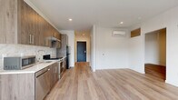 Located at 20 George St in New Haven, CT, this modern one-bedroom, one-bathroom unit offers a thoughtfully designed layout with clean, contemporary finishes. Light wood plank flooring runs throughout the space, creating a warm and cohesive aesthetic from room to room. The open-plan kitchen and living area form the heart of the unit, with the kitchen featuring wood-tone cabinetry, a marble-style tile backsplash, light countertops, and a full suite of stainless steel appliances including a range, refrigerator, and dishwasher. Recessed lighting illuminates the combined living and kitchen area, which benefits from large floor-to-ceiling windows that flood the space with natural light and offer open views of the surrounding cityscape. A wall-mounted mini-split system provides efficient climate control in both the living area and bedroom. The bedroom is a well-proportioned retreat with its own mini-split unit, a dedicated closet, and access to natural light. The bathroom is finished with tile flooring, a wood-tone vanity with an undermount sink and light countertop, and a large mirror. The unit's modern design, quality materials, and practical layout make it a refined and functional living space in the heart of New Haven.