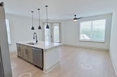 Located at 13111 Tadeo Drive in Charlotte, NC, this 1,200 sq ft single-floor apartment features 3 bedrooms, 2 bathrooms, and a thoughtfully designed open-concept layout. The kitchen and living area serve as the heart of the home, showcasing a large center island with a white quartz countertop, stainless steel appliances including a refrigerator, stove, and microwave, two-tone cabinetry in white and gray, a subway tile backsplash, and three matte black pendant lights that add a modern industrial touch. Light wood-look flooring flows throughout the entire unit. The bedrooms are bright and airy, each featuring large windows with horizontal blinds that invite abundant natural light and outdoor views, as well as ceiling fans. The 190 sq ft primary bedroom connects to a well-equipped en suite bathroom with a double-sink vanity, gray shaker cabinetry, black hardware accents, a glass-enclosed shower, and a walk-in closet featuring built-in shelving and dual hanging rods. The second bathroom mirrors the same design aesthetic with a tub-shower combo, gray vanity, and black fixtures. Two closets throughout the unit offer built-in organizational systems, maximizing storage efficiency across the home.