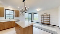 Located at 300 Anthem Dr in Huxley, Iowa, this well-designed two-bedroom, two-bathroom residence offers a thoughtfully laid-out single-floor plan with a clean, contemporary aesthetic throughout. The open-concept kitchen is a standout feature, showcasing warm wood-grain flat-panel cabinetry, crisp white quartz countertops, stainless steel appliances including a range, microwave, and dishwasher, and a central island with a stylish pendant light fixture overhead. Light hardwood-style flooring flows seamlessly throughout the entire residence, enhancing the bright, airy atmosphere. Both bedrooms are well-proportioned and bathed in natural light through large black-framed windows that frame picturesque views of the surrounding Iowa landscape. The primary bedroom offers a generous footprint with direct access to a dedicated bathroom. The second full bathroom features a tub-shower combination with a curved rod, a white vanity, and clean, minimalist finishes. A dedicated closet and hallway provide practical storage and circulation. Throughout the residence, bold black door and window trim creates a striking contrast against the white walls, lending the space a modern, polished character. The overall ambiance is calm, contemporary, and move-in ready.