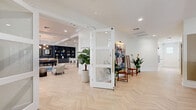 This expansive 2,740 square foot space in Coconut Creek, Florida, is a testament to modern design and multifunctionality. The interior showcases a harmonious blend of entertainment and relaxation areas. A spacious living area features a striking coffered ceiling, recessed lighting, and a large-screen TV, complemented by comfortable seating in vibrant orange tones. The room flows seamlessly into a dining space, creating an open-concept feel.

A game room adds a playful element with a white foosball table and a high-tech golf simulator, perfect for leisure activities. The space also includes a dedicated area with colorful carpeting, possibly for yoga or light exercise. A mezzanine level overlooks the main floor, adding depth and dimension to the overall layout.

The decor is a mix of contemporary and mid-century modern influences, with sleek furniture, bold artwork, and strategic use of plants to bring life to the space. Herringbone pattern wood flooring runs throughout, lending warmth and sophistication. Unique features include booth-style seating with a tropical mural backdrop and a retro-style arcade game.

This versatile space is designed to cater to various activities and gatherings, making it an ideal location for community events, corporate functions, or as a high-end residential amenity space. The thoughtful design elements and diverse functional areas create an inviting and dynamic environment suited for both relaxation and entertainment.