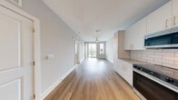 Located at 940 E Adams St in Jacksonville, FL, this well-appointed one-bedroom, one-bathroom unit offers a thoughtfully designed single-floor layout with a clean, modern aesthetic. The open-plan kitchen and living area serves as the heart of the home, showcasing warm hardwood-style flooring, soft gray walls, and track lighting overhead. The kitchen is outfitted with sleek white cabinetry, granite countertops, a classic white subway tile backsplash, and a full suite of stainless steel appliances including a range, microwave, dishwasher, and French door refrigerator. The living area extends to a private balcony through sliding glass doors, inviting natural light and outdoor views into the space. The bedroom is carpeted for comfort, features a ceiling fan, and is brightened by multiple windows with blinds. The bathroom is spacious and well-appointed, featuring dual undermount sinks set into granite countertops, white cabinetry, large mirrors, wood-look flooring, and a glass-enclosed shower. A dedicated closet provides practical storage. The unit combines modern finishes with functional design, creating a comfortable and stylish living environment in the heart of Jacksonville.