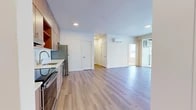 Located at 849 E Magnesium Ave in Spokane, WA, this thoughtfully designed 3-bedroom, 1-bathroom unit offers a clean, contemporary aesthetic throughout its single-floor layout. The open-concept living and kitchen area serves as the heart of the unit, featuring light wood-style luxury vinyl flooring, recessed lighting, and a wall-mounted mini-split system for year-round climate control. The kitchen is outfitted with flat-front wood-toned cabinetry extending to the ceiling, light countertops, a stainless steel refrigerator, electric range, built-in microwave, and dishwasher — all designed for both function and style. The living area flows seamlessly toward large sliding glass doors that open to a private balcony, filling the space with natural light and offering open views of the surrounding landscape. Each of the three bedrooms is carpeted for comfort and features generous windows that bring in additional natural light, with outdoor views visible from multiple rooms. The bathroom is finished with a wood-toned vanity, modern hardware, and a large mirror. A dedicated closet provides practical storage. The unit's neutral color palette, modern finishes, and cohesive design make it a bright and functional living space.