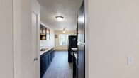 Located at 2040 SW Vermont St in Portland, Oregon, this one-bedroom, one-bathroom apartment offers a practical and comfortable single-floor layout. The combined kitchen and living area forms the heart of the unit, with the living room featuring plush carpeting, a textured ceiling, and a sliding glass door that opens onto a private balcony with pleasant outdoor views of surrounding greenery. The kitchen is outfitted with dark espresso cabinetry, light stone-look countertops, a stainless steel sink, and black appliances including a refrigerator, all set atop wood-look flooring that adds warmth to the space. The bedroom is generously sized, filled with natural light from a window, and includes a built-in sliding-door closet for convenient storage. The bathroom features wood-look flooring, a dark vanity with a stone-look countertop and undermount sink, and a full tub-shower combination. Throughout the unit, neutral warm tones on the walls and textured ceilings create a cohesive and inviting atmosphere. The dedicated closet and efficient layout make this apartment a functional and comfortable home in the SW Portland neighborhood.
