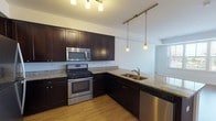 This single-floor unit offers a thoughtfully designed open-concept layout that seamlessly connects the kitchen and living areas. The kitchen is a standout feature, equipped with rich dark-espresso cabinetry, granite countertops, and a full suite of stainless steel appliances, including a gas range, built-in microwave, dishwasher, and refrigerator. A peninsula with an undermount sink and pendant lighting serves as both a functional workspace and a visual divider between the kitchen and the living area. Track lighting above adds further illumination to the space. Light wood-style flooring runs throughout the main living areas, lending warmth and continuity to the open floor plan.

The living area is generously proportioned, benefiting from large windows that invite abundant natural light and offer views of the surrounding neighborhood. The bedrooms are carpeted for comfort and also feature windows that brighten each room. The bathroom is finished with coordinating dark cabinetry, granite countertops, a large mirror, tile flooring, and a full soaking tub with a tiled surround. Overall, the unit presents a cohesive, contemporary aesthetic with consistent finishes and a practical, well-organized layout.