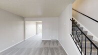 This thoughtfully designed three-floor residence offers a bright and functional layout with a neutral color palette that creates a clean, welcoming atmosphere throughout. The main level features an open living area with plush grey carpeting, a front entry door framed by sheer-curtained windows that fill the space with natural light, and an elegant staircase with decorative wrought iron railing connecting the floors. The kitchen is well-appointed with white shaker-style cabinetry, dark countertops, light wood-look flooring, and a full suite of stainless steel appliances including a range, microwave, refrigerator, and dishwasher. A peninsula with additional counter space adds to the kitchen's functionality. The upper levels host generously sized bedrooms with plush carpeting, ample closet space, and windows providing natural light. The bathroom is finished with wood-look flooring, white cabinetry with dark countertops, and a tub-shower combination. Consistent design elements — including textured ceilings, soft grey carpet, and crisp white trim — unify each level, giving the entire space a cohesive and comfortable character well-suited for everyday living.