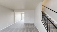 This thoughtfully designed three-floor residence offers a bright and functional layout with a neutral color palette that creates a clean, welcoming atmosphere throughout. The main level features an open living area with plush grey carpeting, a front entry door framed by sheer-curtained windows that fill the space with natural light, and an elegant staircase with decorative wrought iron railing connecting the floors. The kitchen is well-appointed with white shaker-style cabinetry, dark countertops, light wood-look flooring, and a full suite of stainless steel appliances including a range, microwave, refrigerator, and dishwasher. A peninsula with additional counter space adds to the kitchen's functionality. The upper levels host generously sized bedrooms with plush carpeting, ample closet space, and windows providing natural light. The bathroom is finished with wood-look flooring, white cabinetry with dark countertops, and a tub-shower combination. Consistent design elements — including textured ceilings, soft grey carpet, and crisp white trim — unify each level, giving the entire space a cohesive and comfortable character well-suited for everyday living.