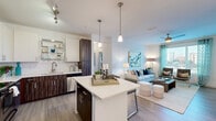 Located at 9301 Summit Centre Way in Maitland, FL, this thoughtfully designed 2-bedroom, 2-bathroom residence offers a comfortable and contemporary living experience across a single floor. The open-concept layout seamlessly connects the kitchen, dining, and living areas, creating a bright and cohesive common space. The kitchen is a standout feature, boasting stainless steel appliances, a center island with a crisp white countertop, two-tone cabinetry with rich wood-grain lower cabinets and white upper cabinets, and wood-style flooring that flows throughout the main living areas. Pendant lighting accents both the island and the dining area, adding a modern touch. The living room is filled with natural light from large windows offering outdoor views, and is completed by a ceiling fan overhead. Both bedrooms are carpeted and well-sized, with the primary bedroom featuring a walk-in closet and a private en-suite bathroom equipped with a glass-enclosed walk-in shower and wood-toned vanity. The second bathroom includes a shower/tub combination and a matching vanity. A dedicated in-unit laundry room with full-size washer and dryer adds everyday convenience. Four closets throughout provide ample storage across this well-organized home.