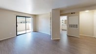 This single-floor residence offers a well-organized layout with a neutral color palette that lends a clean, versatile aesthetic throughout. The open-concept living and dining area is finished with wood-look laminate flooring and features a sliding glass door that opens to a private balcony, allowing natural light to fill the space. A built-in shelving column divides the living area, adding a subtle architectural detail while maintaining an open feel.

The kitchen is accessible via a breakfast bar pass-through, outfitting the space with white cabinetry, a coil-burner electric range, and speckled countertops. A hallway connects the main living area to the private quarters, where carpeted bedrooms offer a comfortable, quiet retreat. At least one bedroom includes a standard reach-in closet with a shelf and hanging rod.

Two bathrooms serve the unit, each featuring wood-look flooring, a shower with a curtain rod, and a toilet. One bathroom includes a vanity with a wide mirror and lighted fixture above, white cabinetry below, and a speckled countertop matching the kitchen. Textured walls are consistent throughout, contributing to the unit's cohesive, understated design.