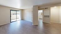 This single-floor residence offers a well-organized layout with a neutral color palette that lends a clean, versatile aesthetic throughout. The open-concept living and dining area is finished with wood-look laminate flooring and features a sliding glass door that opens to a private balcony, allowing natural light to fill the space. A built-in shelving column divides the living area, adding a subtle architectural detail while maintaining an open feel.

The kitchen is accessible via a breakfast bar pass-through, outfitting the space with white cabinetry, a coil-burner electric range, and speckled countertops. A hallway connects the main living area to the private quarters, where carpeted bedrooms offer a comfortable, quiet retreat. At least one bedroom includes a standard reach-in closet with a shelf and hanging rod.

Two bathrooms serve the unit, each featuring wood-look flooring, a shower with a curtain rod, and a toilet. One bathroom includes a vanity with a wide mirror and lighted fixture above, white cabinetry below, and a speckled countertop matching the kitchen. Textured walls are consistent throughout, contributing to the unit's cohesive, understated design.