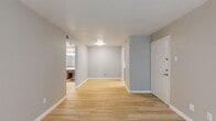 This single-floor space is designed with a clean, functional aesthetic, incorporating a cohesive neutral color palette throughout. Light wood-tone flooring runs through the main living areas, complementing the soft gray and beige walls accented by crisp white baseboards and trim.

The open entryway leads into a generously sized main living area, offering a bright, airy atmosphere with flush-mount ceiling lighting. The layout flows naturally toward the kitchen, which features gray cabinetry with modern hardware, light stone-look countertops, a white subway tile backsplash, and stainless steel appliances including an electric range and over-the-range microwave.

The bedrooms are comfortably sized, with one room showcasing light wood flooring and a window fitted with blinds, while another features plush neutral carpeting and a window that allows natural light to enter. Both rooms offer a calm, restful environment.

The bathroom presents a streamlined design with light wood-tone flooring, a dark-framed vanity with a white countertop and undermount sink, brushed nickel fixtures, and a tub-shower combination enclosed by large-format tile surround. The overall ambiance of the space is clean, understated, and move-in ready.