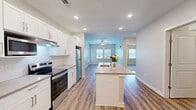 Located at 211 McArthur St in Lawrenceville, GA, this well-appointed 2-bedroom, 2-bathroom residence offers a thoughtfully designed single-floor layout with contemporary finishes throughout. The open-concept kitchen serves as the heart of the home, featuring white shaker cabinetry, stainless steel appliances including a refrigerator and electric range, recessed lighting, and a center island with a built-in sink and quartz-style countertop — ideal for both cooking and casual dining. The kitchen flows seamlessly into the living area, which is finished with durable wood-look plank flooring and ceiling fans for year-round comfort. Natural light fills the space through multiple windows fitted with blinds. The entry hallway provides a clean transition into the home, with easy access to a closet. Both bedrooms are carpeted and include ceiling fans and windows that bring in natural light. The primary bedroom connects to a private en-suite bathroom with a single vanity, ample counter space, a large mirror, and a glass-enclosed shower. A dedicated walk-in closet with wire shelving provides generous storage. The second bathroom offers similar modern finishes. Throughout the residence, neutral tones, clean lines, and consistent flooring choices create a cohesive and move-in-ready atmosphere.