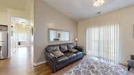 Located at 1094 W Vista Ridge Dr in Lehi, Utah, this well-appointed single-floor home offers three bedrooms and two bathrooms within a thoughtfully designed layout. The living room greets you with vaulted ceilings that lend an airy, open feel, complemented by hardwood-style flooring, a sliding glass door with vertical blinds that invites natural light, and a cozy electric fireplace console. The kitchen is a standout feature, showcasing rich dark-wood cabinetry, light countertops, stainless steel appliances including a full-size refrigerator, a built-in dishwasher, and a central island with bar seating — perfect for casual dining or meal prep. A dedicated dining nook adjacent to the kitchen provides a comfortable space for meals. The bedrooms are carpeted for warmth, with the secondary bedrooms offering ample natural light through large windows. The primary bedroom includes a closet for convenient storage. The bathrooms feature tile flooring, dark-wood vanities with light countertops, and one includes open built-in shelving for linens. A hallway connects the rooms efficiently, completing this functional and inviting single-story home.