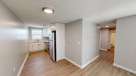 Located at 266 Main St in Windsor Locks, CT, this two-bedroom, one-bathroom residence is thoughtfully laid out across a single floor. The interior features light-toned luxury vinyl plank flooring throughout the main living areas and bedrooms, complemented by neutral gray walls and clean white trim that create a bright, cohesive aesthetic.

The kitchen is well-appointed with white shaker-style cabinetry, a stainless steel refrigerator, stainless steel range, and a built-in microwave. A window above the sink allows for natural light to fill the space. The kitchen flows openly toward the living area, which is generously sized and receives abundant natural light through a wide set of double-hung windows with blinds.

The primary bedroom is a comfortable size, offering two double-door closets and plush carpeting. The second bedroom also features carpeting, a closet, and a window with views to the exterior. Both bedrooms maintain the same neutral color palette seen throughout the home.

The bathroom includes a full tub-shower combo with white tile surround and brushed nickel fixtures, accented by textured walls. Additional storage is provided by two closets located within the unit. The overall ambiance is clean, move-in ready, and practical, making this a functional and well-maintained residence.