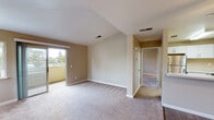 This single-floor residence offers a thoughtfully laid-out living space with a warm, neutral color palette throughout. The main living area is generously sized, featuring plush carpeting, vaulted ceilings, and a ceiling fan that enhances the airy feel. Large sliding glass doors open directly onto a private balcony, flooding the room with natural light and providing pleasant outdoor views of surrounding trees and greenery. An additional window further brightens the space.

The kitchen is well-equipped with crisp white shaker-style cabinetry, light speckled countertops, and stainless steel appliances including an electric range and over-the-range microwave. Wood-look flooring grounds the kitchen area, which transitions seamlessly into the adjoining dining and entry spaces.

The bedroom is a comfortable retreat with carpeted flooring, a ceiling fan, and a sliding closet with built-in shelving for ample storage. Natural light enters through a sizable window. A secondary carpeted room provides additional flexible space.

The bathroom features a white vanity with under-sink storage, a lighted mirror, and wood-look flooring, presenting a clean and modern aesthetic. Throughout the residence, consistent neutral tones and updated finishes create a cohesive and inviting atmosphere.