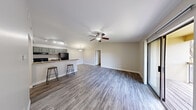 This 2-bedroom, 2-bathroom single-floor residence offers a well-designed layout that maximizes its comfortable footprint. The open-concept living and kitchen area serves as the heart of the home, featuring durable wood-style plank flooring throughout and a ceiling fan overhead. A sliding glass door floods the living space with natural light and opens to a private balcony with exterior views. The kitchen is equipped with gray cabinetry, black appliances including a refrigerator and range, granite-style countertops, a track lighting system, and a peninsula with bar seating — ideal for casual dining or entertaining. Both bedrooms are carpeted and feature ceiling fans, with the primary bedroom offering a notably spacious layout. Each of the two bathrooms is consistently appointed with granite-style vanity countertops, gray cabinetry, a full tub-shower combination, a large mirror, and hardwood-style flooring. Additional features include two closets for storage and a connecting hallway that links the private and shared spaces of the home. Neutral wall tones throughout create a cohesive and move-in-ready ambiance.