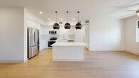 Located in Palm Desert, California, this well-appointed single-story home offers three bedrooms and two bathrooms within a thoughtfully designed floor plan. The open-concept layout connects the kitchen and living areas seamlessly, creating a bright and airy atmosphere enhanced by light hardwood flooring and crisp white walls throughout.

The kitchen is a standout feature, showcasing floor-to-ceiling white cabinetry, a large quartz-topped island, and a striking trio of matte black globe pendant lights. A geometric patterned tile backsplash adds texture, while a full suite of stainless steel appliances — including a refrigerator, range, microwave, and dishwasher — provides practical functionality. The adjacent living area benefits from natural light through large windows and is equipped with a ceiling fan for year-round comfort.

Each bedroom is carpeted for warmth and comfort, with ceiling fans and windows that allow natural light to fill the rooms. The generously sized primary bedroom includes a walk-in closet with built-in shelving and hanging rods. Secondary bedrooms feature their own closet storage. The bathrooms are finished in a clean, modern style with white vanities, large mirrors, hardwood-style flooring, and a tub-shower combination. A connecting hallway ties the rooms together efficiently, completing this well-organized and contemporary home.