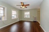 Located at 105 Ward Pkwy in Kansas City, Missouri, this single-floor unit offers a well-organized layout with a variety of functional living spaces. The main living area is a standout, featuring rich, dark hardwood floors that add warmth and depth to the room. Soft sage-green walls complement the natural light streaming in through multiple windows fitted with blinds, while a ceiling fan with a light fixture overhead provides both comfort and illumination. The kitchen is centrally positioned within the layout, outfitted with warm wood-toned cabinetry, a double-basin sink, and a compact, efficient workspace. Adjacent areas transition seamlessly between hard flooring and plush carpeting. The bedrooms are carpeted for comfort and each feature ceiling fans and generous closet space, with one bedroom offering multiple built-in closets with shelving and hanging rods. The bathroom is clean and straightforward, with a full soaking tub and shower combination, a wall-mounted vanity, and a medicine cabinet. Throughout the unit, white trim and neutral tones create a cohesive, understated aesthetic. The open flow between spaces and the abundance of natural light make this a bright, practical, and comfortable home.