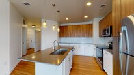 Located at 110 E South Boulder Rd in Lafayette, Colorado, this single-floor unit offers a thoughtfully designed layout with modern finishes throughout. The kitchen serves as a central highlight, featuring a large island with an undermount sink and gray quartz countertops, complemented by pendant lighting overhead. Upper cabinetry in warm wood tones contrasts with crisp white lower cabinets, while a white subway tile backsplash ties the design together. Stainless steel appliances, including a range, microwave, and refrigerator, complete the functional and stylish space. Light bamboo hardwood flooring flows throughout the main living areas, enhancing the bright, airy atmosphere.

The living area is generously sized, with multiple windows allowing abundant natural light and a glass door providing direct access to a balcony with open views of the surrounding landscape. A ceiling fan adds comfort to the space.

The bedroom is carpeted and features a ceiling fan, a window with outdoor views, and access to a spacious walk-in closet equipped with wire shelving for ample storage. The bathroom includes a tub-shower combination with white tile surround, hardwood flooring, and a vanity with a gray countertop and undermount sink.