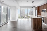 Located in the heart of Toronto at 8 Gloucester Street, this 2-bedroom, 2-bathroom unit offers a well-designed layout across a single floor. Light hardwood-style flooring runs throughout, complemented by crisp white walls that create a bright, cohesive aesthetic.

The open-concept kitchen is a standout feature, showcasing warm wood-grain cabinetry extending to the ceiling, white quartz countertops, stainless steel appliances, and a central island with a sleek pendant track light overhead. Floor-to-ceiling windows flood the kitchen and living areas with natural light while framing impressive views of Toronto's downtown skyline.

The primary bedroom is a comfortable retreat, and the second bedroom doubles effectively as a flexible workspace, equipped with a built-in desk and shelving unit. A dedicated closet provides practical storage.

Both bathrooms are finished with large-format grey tile work. The main bathroom features a soaker tub surrounded by full-height tiling, while the second bathroom offers a glass-enclosed walk-in shower with chrome fixtures and wood-accented cabinetry.

A central hallway connects all rooms efficiently, and recessed lighting throughout ensures consistent illumination. The overall ambiance is modern and polished, ideal for urban living in one of Toronto's most vibrant neighbourhoods.