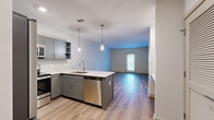 Located at 1015 Gant Hill Drive in Brentwood, Tennessee, this single-floor, one-bedroom, one-bathroom residence offers a thoughtfully designed layout with modern finishes throughout. The open-concept kitchen flows seamlessly into the living area, creating an inviting and functional shared space. The kitchen is outfitted with gray shaker-style cabinetry, white quartz countertops, a herringbone tile backsplash, stainless steel appliances including a refrigerator, range, microwave, and dishwasher, and stylish pendant lighting above the sink peninsula. Hardwood-style plank flooring runs through the main living areas, adding warmth and continuity. The living room is bright and open, featuring a glass-paned door that allows natural light to pour in and offers outdoor views. The bedroom is carpeted for comfort and includes a ceiling fan, a large window with outdoor views, and a closet for storage. The bathroom is clean and functional, featuring a full tub-shower combo with built-in shelving and tile flooring. A dedicated laundry area accommodates a stacked washer and dryer unit, providing added convenience. The overall design is contemporary and clean, with neutral tones creating a calm, welcoming ambiance throughout.