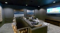 This single-floor space is designed as an intimate entertainment or lounge area with a distinctly dramatic aesthetic. The dark ceiling and deep-toned walls create an enveloping, theater-like atmosphere that sets the tone throughout. Recessed lighting provides focused illumination, casting a warm glow that highlights key design elements without disrupting the moody ambiance.

The centerpiece of the room is a large, deep-gray sectional sofa, generously sized and accented with decorative throw pillows in neutral and plaid patterns. The seating arrangement is oriented around a cluster of uniquely shaped, puzzle-piece-style white accent tables and a wicker-accented coffee table, creating a functional yet visually interesting focal point.

Two large framed paintings featuring abstract seascape imagery in navy, gray, and gold tones anchor the walls, adding a sophisticated artistic element. Paneled wall detailing between the artworks adds architectural depth and structure.

A bar-height counter or display shelf runs along one side of the room, accompanied by white slatted chairs, suggesting a secondary social or serving area. A wooden media console is visible near the entrance, complementing the space's layered, well-appointed design.