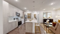 Located at 4540 Kittredge St in Denver, Colorado, this well-appointed 2-bedroom, 2-bathroom residence offers a thoughtfully designed single-floor layout. The open-concept kitchen and living area serves as the heart of the home, featuring light wood-toned cabinetry, a striking mosaic tile backsplash, stainless steel appliances, and a large center island with a white quartz countertop and bar seating — ideal for both cooking and entertaining. Elegant teardrop pendant lights hang above the island, adding a contemporary touch. Rich hardwood-style flooring runs throughout the main living areas, transitioning seamlessly into the connected dining and living spaces, which are bathed in natural light from generously sized windows dressed with sheer curtains. The living room offers a comfortable, open atmosphere. The primary bedroom is a well-sized retreat with plush carpeting, multiple windows, and ample natural light. The second bedroom mirrors this comfortable aesthetic. Both bathrooms are finished with modern fixtures, including a backlit vanity mirror, wood-toned cabinetry with dark countertops, and a full tub-shower combo with clean tile surrounds. Two closets provide practical storage throughout. The overall ambiance is clean, modern, and warm.