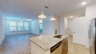 This well-designed single-floor residence offers a clean, contemporary aesthetic throughout. The open-concept layout centers around a fully equipped kitchen featuring a large granite-topped island with an undermount sink, modern pendant lighting, warm wood-tone cabinetry, a subway tile backsplash, and a full suite of stainless steel appliances including a refrigerator with ice maker, range, and microwave. Light wood-style flooring runs throughout the main living areas, enhancing the bright and airy atmosphere created by crisp white walls and recessed lighting.

The spacious living area flows naturally from the kitchen, offering generous room for comfortable furnishing arrangements. Bedrooms are carpeted for warmth and comfort, each featuring ceiling fans and multiple windows fitted with blinds that allow for adjustable natural light. The bathrooms are finished with granite-topped vanities, wood-tone cabinetry, tile flooring, and full soaking tub and shower combinations with white subway tile surrounds.

A dedicated laundry area with a full-size washer is conveniently located adjacent to the kitchen. The thoughtful floor plan connects all rooms through well-proportioned hallways, and ample closet and storage space is provided throughout. The overall design is modern, functional, and move-in ready.