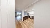 This thoughtfully designed one-bedroom, one-bathroom unit offers a well-organized single-floor layout comprising a living room, kitchen, bedroom, bathroom, and hallway. Light-toned hardwood flooring flows continuously throughout, creating a cohesive and clean aesthetic across all areas.

The kitchen is a standout feature, equipped with two-tone cabinetry—dark espresso lower cabinets paired with crisp white upper cabinets—complemented by light stone countertops and a full suite of stainless steel appliances, including a refrigerator, dishwasher, electric range, and microwave. A central island provides additional prep and storage space. Recessed lighting enhances the kitchen's modern character.

The living room is generously proportioned, benefiting from large floor-to-ceiling windows and a sliding door that invite abundant natural light and offer views of the surrounding cityscape. Neutral-toned walls throughout maintain a bright, airy atmosphere.

The bedroom is a comfortable size, featuring a window with outdoor views, a built-in closet, and the same warm hardwood flooring. The bathroom includes a full soaker tub with overhead shower, finished with clean white tile surround and chrome fixtures, maintaining the unit's consistent, modern aesthetic.
