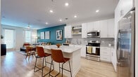 This thoughtfully designed 1-bedroom, 1-bathroom residence offers a cohesive open-concept layout that seamlessly connects the kitchen, dining, and living areas. The kitchen is a standout feature, showcasing crisp white cabinetry, granite countertops, a subway tile backsplash, stainless steel appliances, and a central island with bar seating — ideal for both cooking and casual dining. Light wood-style flooring runs throughout the main living areas, enhancing the bright, airy atmosphere created by recessed lighting and natural light from multiple windows. The living room is anchored by a bold teal accent wall, adding a pop of color that complements the neutral finishes throughout. The spacious primary bedroom features plush carpet, a vibrant mustard yellow accent wall, generous natural light from a large window, and direct access to the full bathroom. The bathroom is well-appointed with a dual-sink vanity topped with granite countertops, white cabinetry, a soaking tub with tiled surround, and continued light wood-style flooring. The overall design balances modern aesthetics with warm, livable touches, creating a comfortable and stylish living environment throughout.