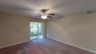 This single-story space offers a practical and comfortable layout with distinct living areas, each finished with attention to functionality. The main living area is generously sized, featuring soft carpeting, neutral wall tones, a textured ceiling, and a ceiling fan with integrated lighting. A sliding glass door opens to a private balcony, allowing natural light to fill the room and providing an outdoor view of surrounding greenery.

The kitchen is designed for efficiency, featuring a galley-style layout with warm oak cabinetry, granite-look countertops, and hardwood flooring. Stainless steel appliances, including an electric range and a full-size refrigerator, complement the double-basin sink and dishwasher. Ample upper and lower cabinet storage adds to the kitchen's practicality.

The bedroom areas are carpeted and well-lit by natural light through windows with blinds. The primary bedroom connects to an en-suite bathroom appointed with dual sinks set in an oak vanity with granite-look countertops, a soaking tub, hardwood floors, and generous built-in shelving. A dedicated in-unit laundry area accommodates a full-size washer and dryer. The entry foyer provides a welcoming transition into the main living space via hardwood flooring.
