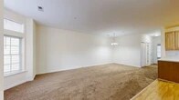 Located at 1200 Regency Ct in Middletown, NY, this single-floor residence offers a thoughtfully designed layout with one bedroom, two bathrooms, and a den. The expansive combined living and dining area is a standout feature, showcasing plush wall-to-wall carpeting, crisp white walls, and a decorative pendant chandelier overhead. A striking curved bay window arrangement floods the living space with natural light and provides pleasant outdoor views, creating an airy and welcoming atmosphere.

The kitchen is outfitted with warm honey-toned wood cabinetry, light countertops, hardwood-style flooring, and stainless steel appliances including a dishwasher, offering a clean and functional workspace. A pantry and utility room add practical storage and convenience.

The generously sized primary bedroom features soft carpeting and a large window that brings in natural light and outdoor views. The den provides flexible additional living space. Three closets throughout the unit ensure ample storage.

The two bathrooms are finished in neutral tones; one features a full tub/shower surround with chrome fixtures, while the other includes a wood-vanity with a wide mirror. A dedicated laundry area and hallway complete this well-organized and comfortable residence.