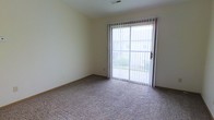Located at 1237 Watermark Drive in Lancaster, Ohio, this single-story residence offers a straightforward and functional layout well-suited for comfortable everyday living. The interior features wall-to-wall carpeting throughout the living area, providing a warm and cushioned underfoot experience. Neutral-toned walls create a clean, versatile backdrop that accommodates a variety of décor styles. A notable feature of the main living area is the full-width sliding glass door, dressed with vertical blinds, which serves as both a source of abundant natural light and a direct point of access to the outdoors. Views through the glass door reveal a green outdoor area, adding a pleasant connection to the surrounding landscape. The ceiling includes a visible HVAC vent, indicating a centralized climate control system for year-round comfort. The overall design is simple and uncluttered, emphasizing practicality and ease of use. The single-floor layout ensures convenient accessibility throughout, making movement between spaces effortless. This residence presents a solid, no-frills living environment in a residential setting within Lancaster, Ohio.