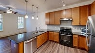 This 560 square foot apartment in Charlotte, NC, offers a compact yet functional living space. The single-floor layout comprises one bedroom, one bathroom, and an open-concept living area. The kitchen is a standout feature, boasting warm wood cabinetry, sleek stainless steel appliances, and a granite countertop with a breakfast bar. Pendant lighting adds a touch of modern elegance.

The bathroom is designed for accessibility, with grab bars and a spacious layout. It features clean, white tiles and a contemporary aesthetic. The bedroom, measuring 130 square feet, includes carpeting for comfort and windows for natural light. Throughout the apartment, you'll find a mix of durable wood-look flooring and carpet, creating distinct zones within the open plan.

Large windows with horizontal blinds allow for ample natural light and privacy control. The overall design aesthetic is modern and minimalist, with crisp white walls that contribute to a sense of spaciousness. Despite its compact size, the apartment's thoughtful layout and high-quality finishes make it feel both comfortable and stylish, ideal for urban living in Charlotte's vibrant Euclid Avenue neighborhood.
