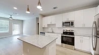 Located at 350 Bay Laurel Dr in Saint Augustine, FL, this single-story, 3-bedroom, 2-bathroom home offers a well-designed layout with modern finishes throughout. The open-concept kitchen and living area serves as the heart of the home, showcasing crisp white shaker cabinetry, a subway tile backsplash, granite countertops, and a central island with pendant lighting overhead. Stainless steel appliances — including a range, built-in microwave, dishwasher, and refrigerator — complete the kitchen. Light wood-look flooring runs through the main living areas, adding warmth and continuity. The three bedrooms feature plush carpeting, ceiling fans, and windows that invite natural light. The spacious primary bedroom includes a walk-in closet with wire shelving for organized storage. Both bathrooms are finished with granite-top vanities, white cabinetry, and tile-surround tub-shower combinations set on wood-look flooring. A dedicated laundry room houses a full-size top-load washer and dryer. Neutral wall tones and clean white trim throughout create a bright, cohesive aesthetic, making this home a functional and comfortable residence in the Saint Augustine area.