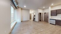 This 560-square-foot, one-bedroom, one-bathroom apartment is located at 2939 Smallman St in Pittsburgh's vibrant Strip District. The open-concept kitchen and living area features light hardwood-style flooring, recessed lighting, and exposed ductwork that lends an industrial character to the space. The kitchen is well-appointed with dark espresso cabinetry, white quartz countertops, a subway tile backsplash, and a full suite of stainless steel appliances including a French door refrigerator with water dispenser, electric range, over-the-range microwave, and dishwasher. The living area benefits from oversized floor-to-ceiling windows that frame views of the neighboring brick architecture and fill the space with natural light. The 110-square-foot bedroom features plush carpeting, a large picture window, and direct access to a dedicated closet. The bathroom includes a full soaking tub and shower combination, a stone-top vanity with dark wood cabinetry, and a large frameless mirror. A convenient in-unit stacked washer and dryer completes this thoughtfully designed urban apartment.