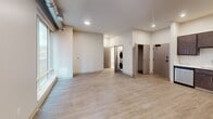 This 560-square-foot, one-bedroom, one-bathroom apartment is located at 2939 Smallman St in Pittsburgh's vibrant Strip District. The open-concept kitchen and living area features light hardwood-style flooring, recessed lighting, and exposed ductwork that lends an industrial character to the space. The kitchen is well-appointed with dark espresso cabinetry, white quartz countertops, a subway tile backsplash, and a full suite of stainless steel appliances including a French door refrigerator with water dispenser, electric range, over-the-range microwave, and dishwasher. The living area benefits from oversized floor-to-ceiling windows that frame views of the neighboring brick architecture and fill the space with natural light. The 110-square-foot bedroom features plush carpeting, a large picture window, and direct access to a dedicated closet. The bathroom includes a full soaking tub and shower combination, a stone-top vanity with dark wood cabinetry, and a large frameless mirror. A convenient in-unit stacked washer and dryer completes this thoughtfully designed urban apartment.
