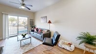 Located at 1980 Aquarena Springs Dr in San Marcos, TX, this well-appointed 5-bedroom, 4-bathroom unit offers a thoughtfully designed single-floor layout perfect for group living. The open-concept kitchen and living area serves as the heart of the home, featuring taupe cabinetry with brushed nickel hardware, light granite countertops, a tile backsplash, and a full suite of black appliances including a range, microwave, dishwasher, and refrigerator. A peninsula with seating provides a casual dining option, while wood-look flooring flows throughout the main living areas, adding warmth and cohesion. The living room is bright and airy, highlighted by a sliding glass door that opens to a private balcony with outdoor views. Each of the five bedrooms offers carpeted flooring and generous natural light through large windows, with the primary bedroom providing a comfortable, well-proportioned retreat with closet space. The four bathrooms are clean and functional, each featuring wood-look tile flooring, granite-topped vanities with dark wood cabinetry, and a full tub-shower combination. A hallway connects the private quarters to the shared living spaces, creating a practical and efficient floor plan suited for multiple residents.