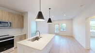 Located at 1095 Union St in Spartanburg, SC, this well-appointed 2-bedroom, 2-bathroom residence offers a thoughtfully designed single-level layout with modern finishes throughout. The open-concept kitchen and living area serves as the heart of the home, anchored by a large center island with a crisp white quartz countertop, undermount stainless steel sink, and two striking matte black pendant lights. The kitchen is outfitted with warm-toned wood cabinetry, stainless steel appliances including a French door refrigerator, over-the-range microwave, and electric range. Light wood-look flooring flows seamlessly throughout, complementing the clean white walls and recessed lighting. The living area receives ample natural light and features a glass door opening to an outdoor balcony. Both bedrooms are generously sized, with the primary suite offering a ceiling fan, direct access to its en-suite bathroom, and a spacious walk-in closet with full wire shelving systems. The primary bathroom features a double-sink vanity with wood cabinetry, white quartz countertops, framed mirrors, and a glass-enclosed shower. The second bedroom also includes ceiling fan access and is served by a well-appointed second bathroom. Additional highlights include five closets, an in-unit laundry area, and a connecting hallway that ties the layout together efficiently.