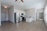 Located at 645 E Bay Street in the heart of Charleston, SC, this single-floor unit blends modern finishes with a clean, contemporary design throughout. The open-concept living and dining area is anchored by warm wood-look laminate flooring, recessed lighting, and a ceiling fan, creating a bright and welcoming atmosphere. Multiple large windows along the living space flood the interior with natural light and offer views of the surrounding neighborhood's lush greenery.

The kitchen is well-appointed with white shaker-style cabinetry, granite countertops with subtle veining, a subway tile backsplash, and a full suite of stainless steel appliances including a range, microwave, refrigerator, and dishwasher. A peninsula with an undermount sink adds additional prep and dining space.

The bedroom is generously proportioned, featuring plush carpeting, multiple windows with views of mature trees, and a large walk-in closet outfitted with wire shelving systems and panel doors. The bathroom is finished with granite-topped cabinetry in a warm gray tone, oil-rubbed bronze fixtures, and a full tub-shower combination with white subway tile surround. The cohesive neutral color palette and quality finishes throughout make this a polished and functional Charleston residence.