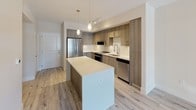 Located at 4200 NW 107 Ave in Doral, Florida, this thoughtfully designed single-floor unit offers a clean, contemporary aesthetic throughout. The open-concept kitchen serves as the centerpiece of the living space, showcasing warm wood-toned cabinetry, quartz countertops, a geometric hexagonal tile backsplash, and a full suite of stainless steel appliances including a range, microwave, dishwasher, and refrigerator. A central island provides additional prep and gathering space, while elegant pendant lighting adds a refined finishing touch. Light wood-look flooring runs seamlessly throughout the unit, creating a cohesive and airy atmosphere. The bedroom features neutral tones, a large window that invites natural light and outdoor views of lush palm trees, and access to a well-organized walk-in closet with built-in shelving. An additional room offers a versatile, flexible space suitable for a variety of uses. The bathroom is finished with classic white subway tile surrounding a full soaking tub and shower combination, complemented by wood-toned vanity cabinetry and light flooring. Crisp white walls and abundant natural light enhance the bright, welcoming ambiance found throughout this modern Doral residence.