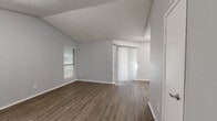 This single-story, 3-bedroom, 2-bathroom home offers a well-organized layout with consistent wood-look flooring and a neutral gray palette throughout. The open living and dining area is a standout space, featuring vaulted ceilings, a tile-surround fireplace, and multiple windows fitted with horizontal blinds that allow for natural light. A sliding glass door provides additional brightness and outdoor access. The galley-style kitchen is efficiently designed with white cabinetry, light quartz countertops, stainless steel appliances including an electric range, microwave, dishwasher, and refrigerator, plus a pantry for added storage. The three bedrooms are comfortably sized, each with wood-look flooring; the primary bedroom includes a ceiling fan and a walk-in closet. The secondary bedrooms are served by closets of their own. Both bathrooms feature clean white finishes with tub-shower combinations and updated vanities with quartz countertops. The home also includes a dedicated laundry area and four closets total, providing ample storage. Textured ceilings are present throughout, adding a consistent architectural detail across all rooms.