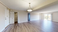 This single-floor residence offers a thoughtfully designed layout that balances open living spaces with functional, well-defined rooms. The main living and dining area is unified by warm hardwood-style flooring and neutral wall tones, creating a bright and inviting atmosphere. A stylish pendant light fixture serves as a focal point, anchoring the dining space while adding a contemporary touch. Natural light filters in through sliding glass doors and windows, enhancing the open feel of the living area.

Adjacent to the dining space, the kitchen is equipped with modern stainless steel appliances, including a gas range and over-the-range microwave. Two-toned cabinetry — white upper cabinets paired with wood-grain lower cabinets — is complemented by clean white countertops and a subtle tile backsplash, giving the kitchen a sleek, updated look. Light tile flooring ties the kitchen aesthetic together seamlessly.

The bedroom features plush carpeting, soft neutral walls, and a window with views of mature trees, offering a calm and restful environment. A closet with louvered doors provides organized storage. The bathroom is finished with large-format beige tile surrounding a soaking tub and shower, paired with chrome fixtures for a clean, modern appearance.

Throughout the space, consistent use of neutral tones, quality materials, and modern lighting creates a cohesive and comfortable living environment.
