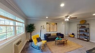 This single-floor residence at Fairfield - The Pines in Riverhead, NY offers a thoughtfully designed layout with consistent finishes throughout. Crown molding frames every room, adding a refined architectural detail that ties the space together cohesively.

The spacious living room features recessed lighting, a ceiling fan, and multiple windows that allow natural light to fill the room. Plush carpeting and neutral gray walls create a versatile backdrop for the area's contemporary styling.

The kitchen is outfitted with rich cherry wood cabinetry, dark granite countertops with a complementary tile backsplash, stainless steel appliances including a refrigerator, dishwasher, and gas range, and dark tile flooring. A connected hallway with open shelving leads seamlessly back toward the living area.

The bedrooms continue the carpeted flooring and crown molding theme, each equipped with ceiling fans and ample closet space. One bedroom features a generous double-door closet alongside an additional door, providing substantial storage.

The bathroom includes a tiled tub-shower combination with sliding glass doors, a dark granite-topped vanity with a cherry wood base, and clean white tile detailing. Overall, the residence presents a polished and comfortable living environment throughout.