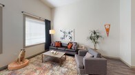 Located at 139 Anderson Hwy in Clemson, SC, this single-floor unit offers a modern, well-designed living experience with striking soaring ceilings that lend an open, airy feel throughout the space.

The kitchen is a functional highlight, featuring light gray cabinetry, a bold navy blue subway tile backsplash, white quartz countertops, stainless steel appliances, and durable wood-look flooring. A generous island provides additional prep and dining space, while track lighting illuminates the room effectively.

The living area is bright and welcoming, with large windows dressed in dark curtains that allow for natural light control. The tall ceilings amplify the sense of space, making the room feel expansive and comfortable.

The bedrooms are carpeted for warmth and comfort, each featuring soaring ceilings, ample closet space, and windows that bring in natural light. The rooms offer a quiet, private retreat with thoughtful layouts.

The bathrooms are clean and contemporary, with light wood-tone vanities, white quartz countertops, large mirrors, and tub-shower combinations fitted with either curtains or surround enclosures. The finishes throughout maintain a cohesive, modern aesthetic.

Overall, this unit presents a polished, contemporary living environment ideally situated near Clemson University.