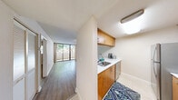 Located at Bull Run Road in the serene community of Miami Lakes, Florida, this well-appointed one-bedroom, one-bathroom unit offers a comfortable and functional layout across a single floor. The living area features warm light wood laminate flooring, neutral-toned walls, a textured ceiling, and track lighting, creating a bright and welcoming atmosphere. A pass-through counter connects the living space to the galley-style kitchen, which is equipped with warm wood cabinetry, white countertops, subway tile backsplash, stainless steel appliances including a refrigerator and range, and tile flooring — offering an efficient and stylish cooking space. The hallway leads to a dedicated closet with louvered doors, providing practical storage. The bedroom is carpeted and features a window with blinds that frames lush greenery outside, lending a calm, natural feel. The full bathroom includes a wooden vanity with a single sink, a wall-mounted mirror, and a separate room with a bathtub and toilet finished in clean white tile. Central air conditioning keeps the space comfortable year-round. A private balcony rounds out this unit, offering an outdoor retreat. This residence combines practical design with warm finishes in a tranquil Miami Lakes setting.
